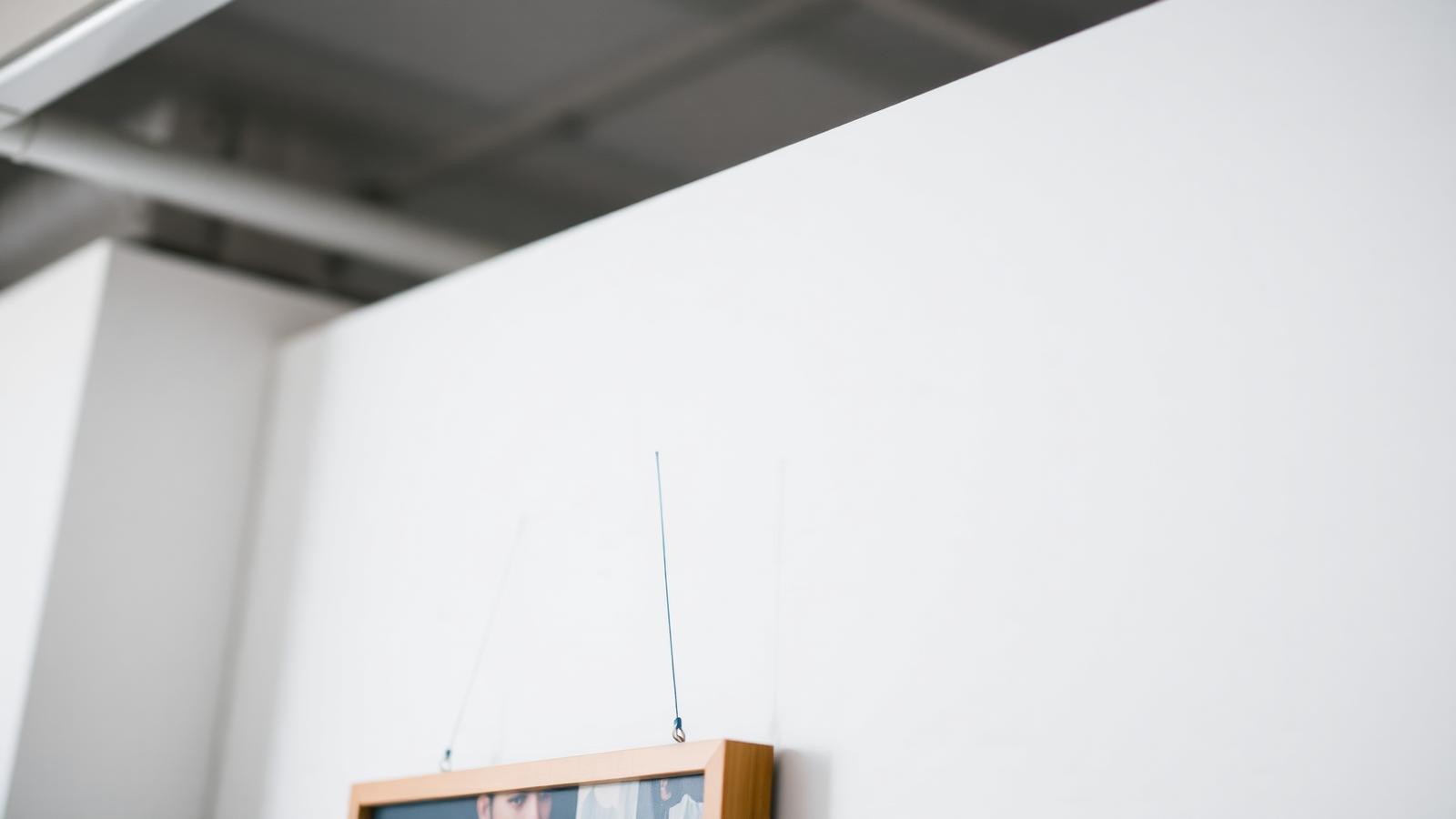 Nærbillede af kunstskinne med wire og krog, der holder et indrammet værk